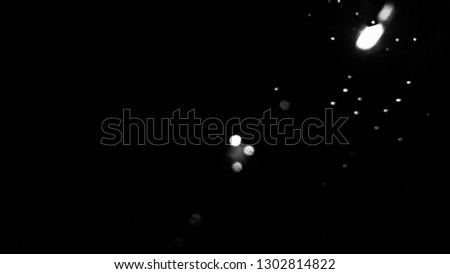 Close-up of rain drop on the glass with sparkle lights background. De focused. High contrast black white silver.
