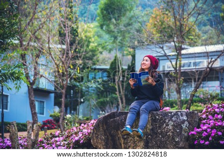 woman travel nature in the flower garden. relax sitting on rocks and reading books In the midst of nature at doi Inthanon.