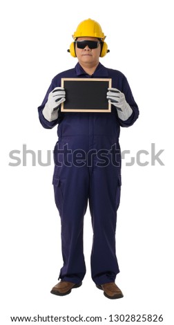 Full body portrait of a worker in Mechanic Jumpsuit with helmet, earmuffs, Protective gloves and Safety goggles holding chalkboard isolated on white background clipping path