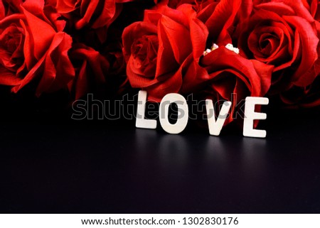 Wooden letters word "LOVE" and red rose on black background. Concept of Valentine's day