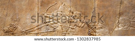 Wall relief from Mesopotamia, Babylon theme. Assyrian and Babylonian art, Ancient panoramic panel with warriors in Ashurbanipal lion hunt. Sumerian civilization, Middle East history and temple concept Royalty-Free Stock Photo #1302837985