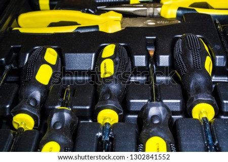 Big tool kit of black and yellow colors for the house in a box. Flat-nose pliers, screw-drivers, stationery knife and nippers. Repair.