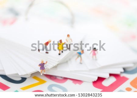 Miniature people: Group of children playing on book with copy space using as education, back to school, boy and girl, children's day concept.