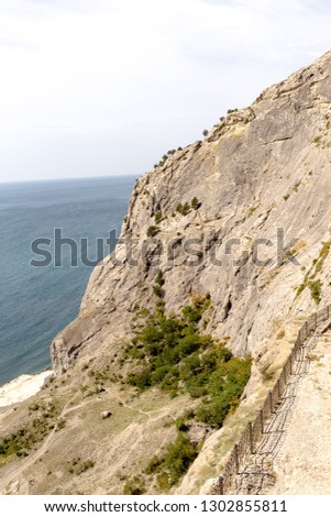 Crimea, Sudak, the old Genoese fortress, side view, overthrown, bottom, on the Black Sea and the beach, houses and people are small, beautiful nature, blue sky and clouds