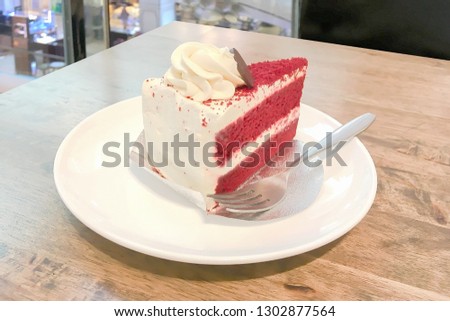Red rose color Valentine milk cake with white cream butter and stainless fork with white plate on wooden table top at holiay night time.