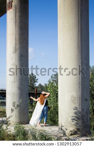 Silhouette of young redhead woman in hat near the column
