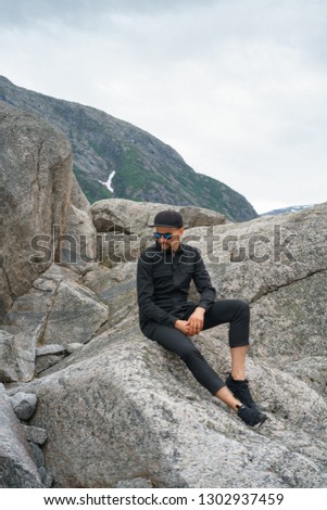 portrait of young traveler rock climber on the background of spellbinding landscape of Norwegian nature with high charming mountains and hills in which it is impossible not to fall in love