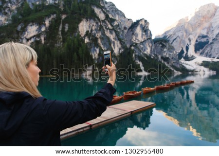 Travel and adventure. Travel hiker makes photo of beautiful landscape on smartphone, Dolomites Mountaines. Braies Lake (Lago di Braies), hiking on alpine lake, Alps, Dolomites, Italy, Europe