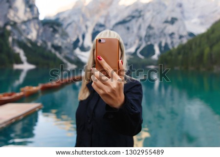 Travel and adventure. Travel hiker makes photo of beautiful landscape on smartphone, Dolomites Mountaines. Braies Lake (Lago di Braies), hiking on alpine lake, Alps, Dolomites, Italy, Europe