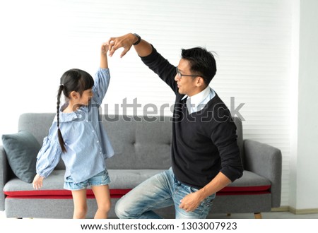 Happy asian father and daughter playing dance together in livingroom at home.