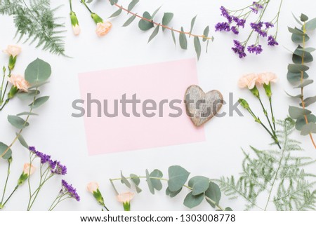 Flowers composition. Paper blank, flowers, eucalyptus branches on pastel  background. Flat lay, top view, copy spaceFlat lay stiil life.