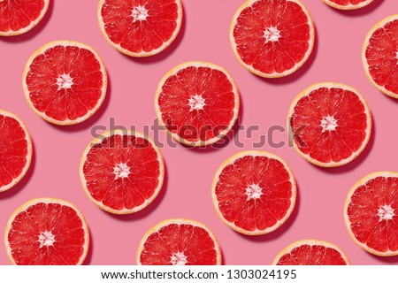 Colorful fruit pattern of fresh grapefruit slices on pink background. Minimal flat lay concept. Royalty-Free Stock Photo #1303024195