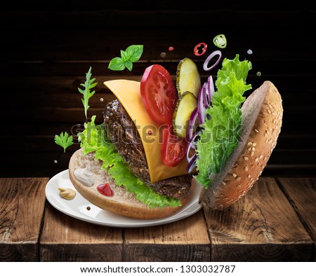 Hamburger ingredients falling down one by one to create a perfect meal. Colorful conceptual picture of burger cooking.