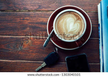 Cup of hot coffee,books,smart phone and keys on the wood plate on top view
