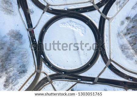 Aerial top down view of roundabout in winter with traffic and snow - Image