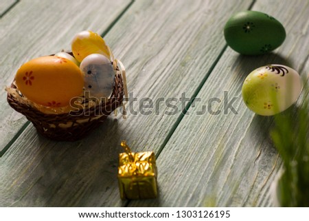 Easter card with painted eggs on the wooden table, with flower and grass