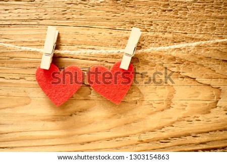 2 two red hearts hanging on a line in front of a brown wooden fence background. happy valentines day. 