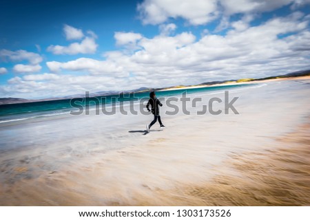 A young woman with curly hair running on Ardara Beach, County Donegal, Ireland
