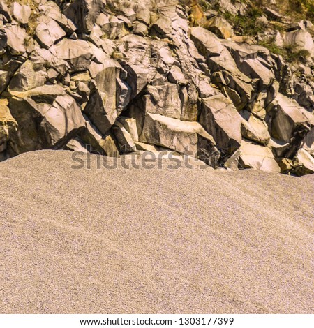 Pile of sand and sharp rock with little vegetation                                 