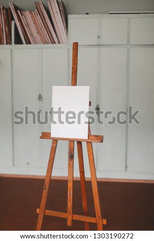 Wooden easel with blank canvas in a art studio. Wooden easel in the room. Minimal style concept.