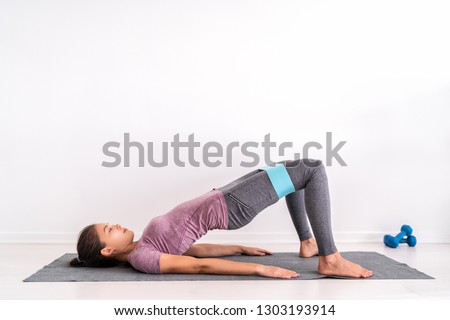 Resistance hoop band exercises Fit girl training on floor doing Glute bridge abduction workout exercise to tone glute muscles and activate weight loss. Royalty-Free Stock Photo #1303193914