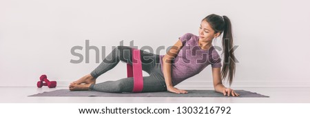 Resistance band clamshell exercise fit girl training legs on floor mat demonstration. Hip abductor workout for burning calories.