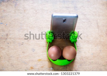phone with green holder with two eggs on the cover of the artist's box