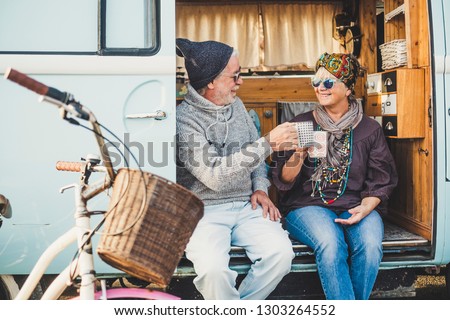 Happy cheerful mature people couple caucasian traceler enjoy and take a break resting sit down out of her van during alternative vacation for nice retired lifestyle together forever with love Royalty-Free Stock Photo #1303264552