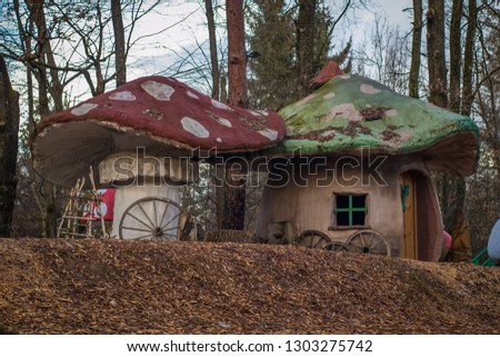Real mushroom houses in a country setting. Mushroom shaped fantasy or children playhouses in an enchanted forest. Red and green roof with white dots.