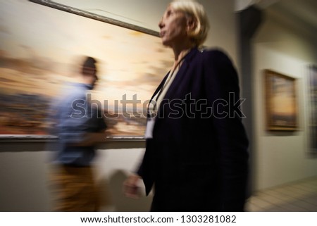 Blurred shapes of people walking in hall of modern art gallery o museum, copy space