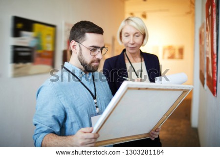 Waist up portrait of modern bearded man buying picture in art gallery or museum, copy space Royalty-Free Stock Photo #1303281184