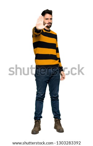 Full-length shot of Handsome man with striped sweater making stop gesture denying a situation that thinks wrong on isolated white background