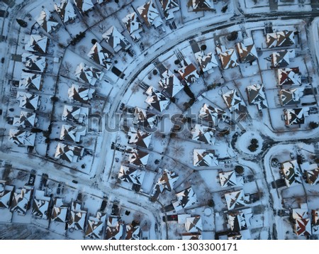 Aerial drone photo, top down, of suburban houses in Oakville, Ontario, Canada everything is white and covered with snow in the sunshine.