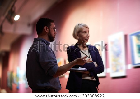 Waist up portrait of two art gallery workers inspecting paintings in museum exhibition Royalty-Free Stock Photo #1303308922
