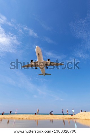 Commercial airplane landing above sea and clear blue sky over beautiful scenery nature background location at mai khao beach phuket thailand,Amazing landmark people take a photo at phuket airport.