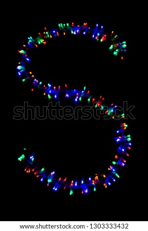The letter "S" of the English alphabet made of multicolored electric garlands on a dark background, blur, bokeh, isolated on black