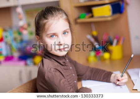 Cute little girl, left-handed, writing her homework at the table