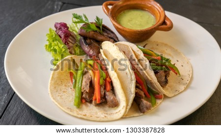 tacos with beef, fresh vegetables and green salsa