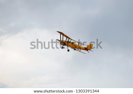 Yellow radio control bi plane doing aerobatic in cloudy sky