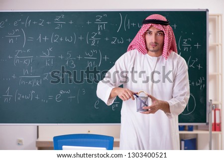 Arab teacher in front of chalkboard 