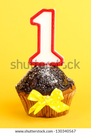 Birthday cupcake with chocolate frosting on yellow background