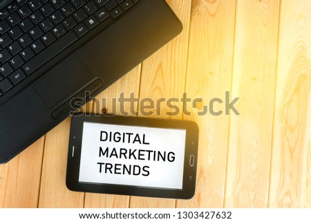 Phone and tablet with text digital marketing trends on wooden background,.