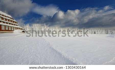 Old house at the ski slope with snow covered in winter in the mountains at blue sky with sun, Czech republic
