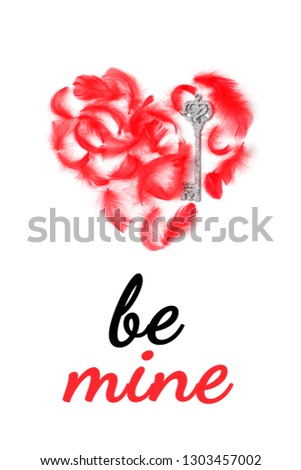 Postcard with the words Be mine in italics. Red heart is laid out of red feathers and decorative silver keys. Top view, flat lay, vertical format