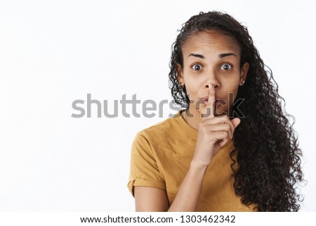 Shh do not slip word. Portrait of thrilled and happy excited cute african-american woman with curly hair showing shush gesture with finger over mouth as hiding secret wanting make surprise