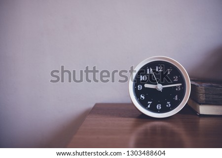 The clock is on table in bedroom