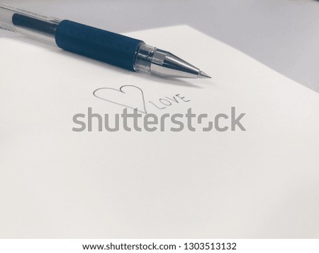 Tip of pen with heart shaped and “love” written lettering on white background