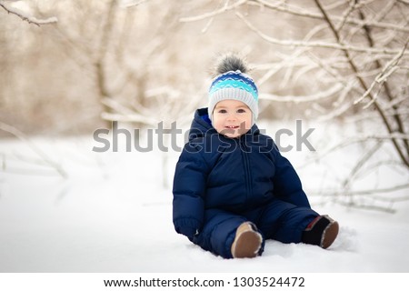 happy smiling baby boy sitting on snow Royalty-Free Stock Photo #1303524472