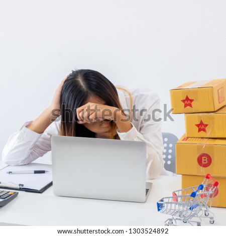 Square frame of online business owner Asian women wear white shirt feel down bad sad online sales declined many boxes of parcel and trolley on the right hand side of table  