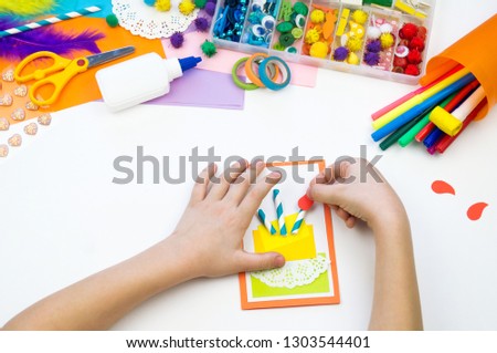 Child makes a postcard with a picture of a cake. Kid paperwork. Material for creativity. Kindergarten and school.